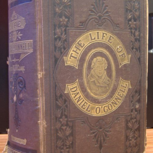 photo of a large maroon book with a cover with black and gold decoration and text surrounding a portrait of Daniel O'Connell that reads "The Life of Daniel O'Connell"
